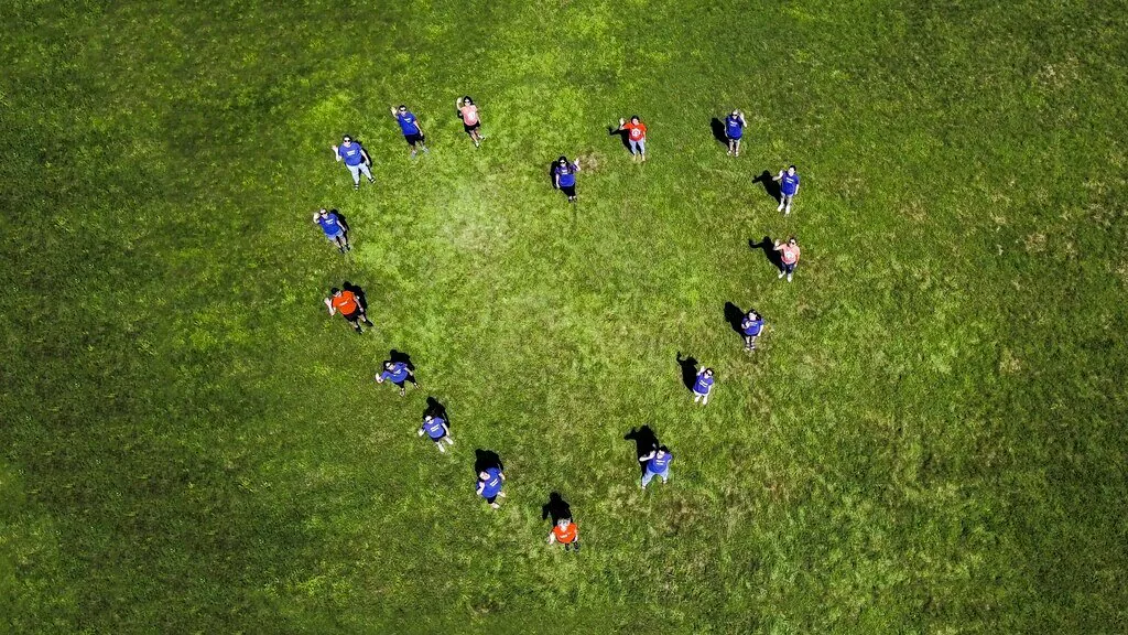 3M employees pictured from above, stand in a heart formation on the grass